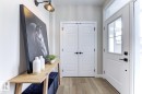 Entryway featuring light wood-finish flooring, a white paneled front door with clear glass inserts and matte black hardware, and a built-in wall sconce - 519 Ashgrove Circle, Leduc, AB 