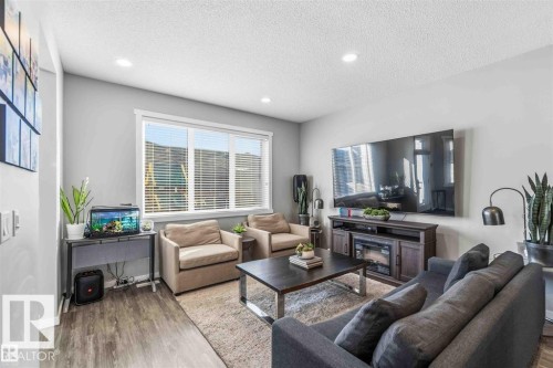 Bright living area featuring wood-finish flooring, light grey walls, and recessed lighting - 1908 25 Street, Edmonton, AB 