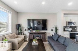 Open-concept living area featuring wood-finish flooring, recessed lighting, and a window with blinds - 