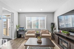 Living area featuring wood-finish flooring, recessed lighting, a large window with blinds, and a built-in media console with an electric fireplace - 