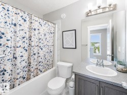 Contemporary bathroom featuring a single vanity with a white oval sink, brushed nickel faucet, and a large frameless mirror - 