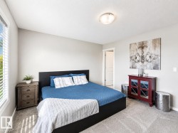 Carpeted bedroom featuring neutral wall tones, a large window with blinds, and a semi-flush ceiling light fixture - 