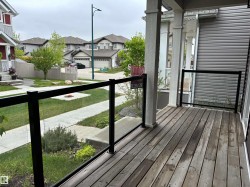 Inviting porch with wood-finish decking, black metal railings, and clear glass panels - 