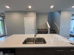 Kitchen island with a double stainless steel sink, chrome faucet, and light-toned countertop - 