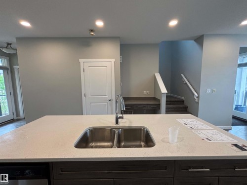 Kitchen island with a double stainless steel sink, chrome faucet, and light-toned countertop - 1908 25 Street Nw, Edmonton, AB 