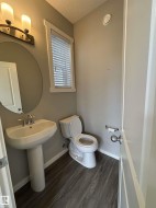 Pedestal sink with chrome faucet, wood-finish flooring, and window with blinds - 