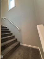 Carpeted staircase with white handrails and a window - 