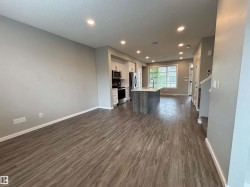 Open-concept living space with wood-finish flooring, recessed lighting, and a modern kitchen island featuring an undermount sink - 