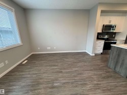 Wood-finish flooring throughout, bright walls, white window blinds, white cabinetry, and stainless steel appliances - 