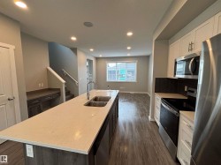 Contemporary kitchen island with a double basin sink, light-toned countertop, and wood-finish cabinetry - 