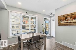 Contemporary dining area featuring a large window with blinds, recessed ceiling lighting, wood-finish flooring, and a white trim package - 
