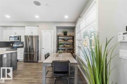 Open-concept dining area featuring wood-finish flooring, recessed lighting, and a window with blinds - 