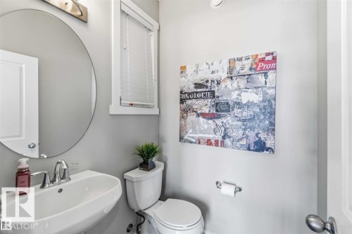 Pedestal sink with chrome fixtures and a circular mirror - 1908 25 Street, Edmonton, AB 