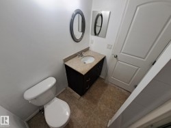 Bathroom featuring a dark wood-finish vanity with a light speckled countertop, an undermount sink, and a chrome faucet - 
