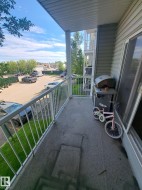 Private balcony with concrete flooring, white metal railing, and light-colored vinyl siding - 