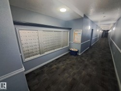 Hallway featuring built-in mailboxes, wall sconce lighting, and patterned carpet flooring - 