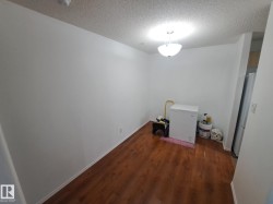 Wood-finish flooring with white baseboards, textured ceiling, and a dome light fixture - 