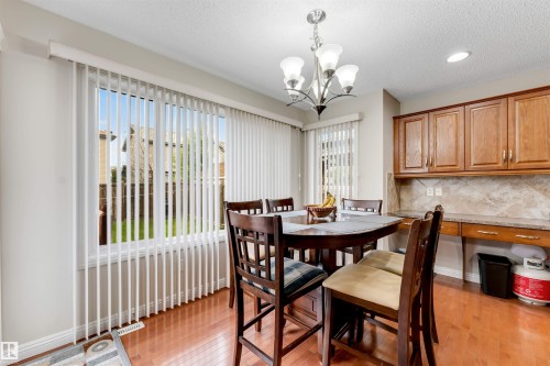 Dining area featuring wood-finish flooring and a contemporary chandelier - 3012 25 Ave Avenue, Edmonton, AB 