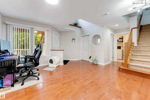 Bright interior featuring wood-finish flooring, a carpeted staircase with wood handrails, and a laundry area with washer and dryer units - 3012 25 Ave Avenue, Edmonton, AB 