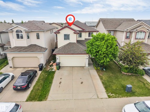 Two-story property featuring a double-car garage, light-colored siding, and a gabled roofline - 3012 25 Ave Avenue, Edmonton, AB 