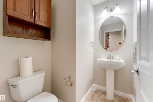 Powder room featuring a pedestal sink, oval mirror, and tile flooring - 3012 25 Ave Avenue, Edmonton, AB 