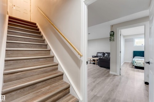 Staircase featuring wood-finish treads and risers, a light-toned wood handrail, and crisp white trim - 3012 25 Ave Avenue, Edmonton, AB 