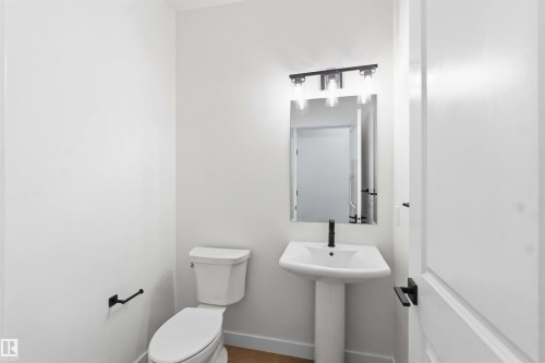 Pedestal sink with matte black faucet, wall-mounted mirror, and contemporary light fixture - 1085 Cristall Crescent, Edmonton, AB 