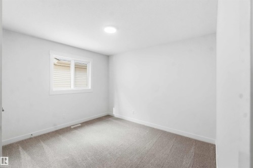 Carpeted room with a white-framed window, white walls, and a ceiling-mounted light fixture - 1085 Cristall Crescent, Edmonton, AB 