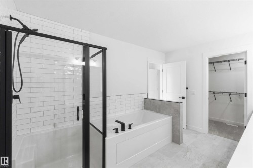 Bathroom featuring a tiled tub-shower combination with matte black fixtures and frameless glass enclosure - 1085 Cristall Crescent, Edmonton, AB 