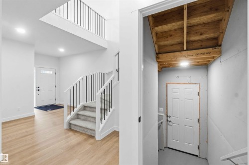 Foyer featuring light wood-finish flooring, a contemporary staircase with black metal balusters, and a second-story open landing - 1085 Cristall Crescent, Edmonton, AB 