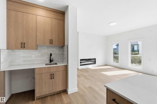 Integrated wet bar featuring wood-finish cabinetry, white countertop, and subway tile backsplash - 1085 Cristall Crescent, Edmonton, AB 