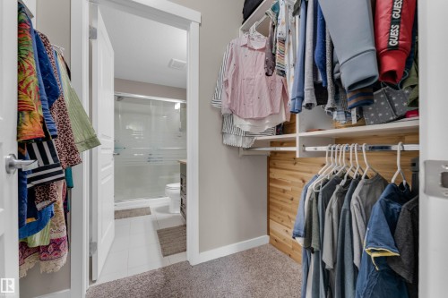Expansive walk-in closet featuring built-in shelving, hanging rods, and a cedar-paneled accent wall - 115 812 Welsh Drive Sw, Edmonton, AB 