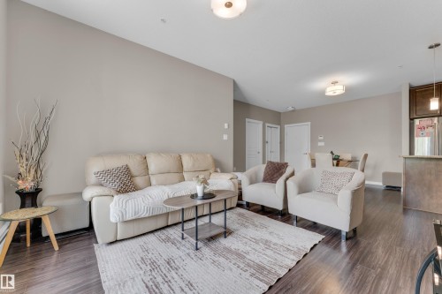Open-concept living area featuring wood-finish flooring, neutral wall tones, recessed lighting, and a kitchen pass-through - 115 812 Welsh Drive Sw, Edmonton, AB 