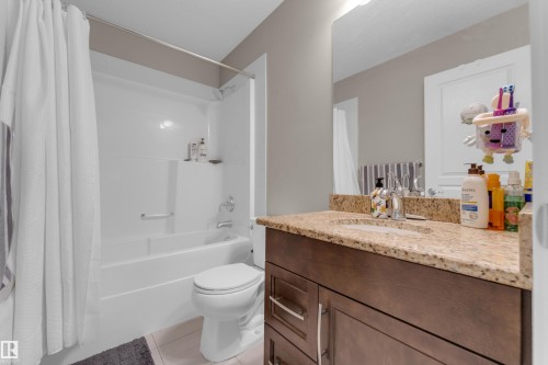 Full bathroom featuring a single vanity with a granite-style countertop, integrated sink, and dark wood-finish cabinetry with silver hardware - 115 812 Welsh Drive Sw, Edmonton, AB 