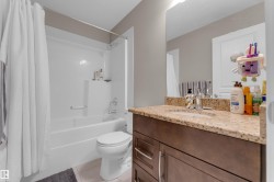 Full bathroom featuring a single vanity with a granite-style countertop, integrated sink, and dark wood-finish cabinetry with silver hardware - 