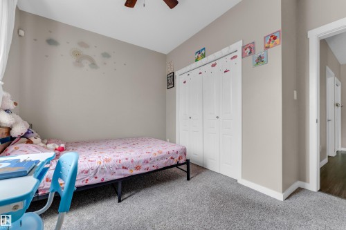 Bedroom featuring neutral tone walls, bi-fold closet doors, and plush grey carpeting - 115 812 Welsh Drive Sw, Edmonton, AB 