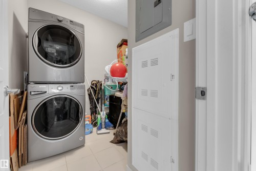 Utility area featuring stacked laundry appliances, tiled flooring, and neutral wall paint - 115 812 Welsh Drive Sw, Edmonton, AB 