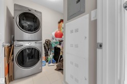 Utility area featuring stacked laundry appliances, tiled flooring, and neutral wall paint - 