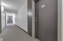Property entrance featuring a solid door with modern hardware, leading to a hallway with patterned carpeting - 115 812 Welsh Drive Sw, Edmonton, AB 