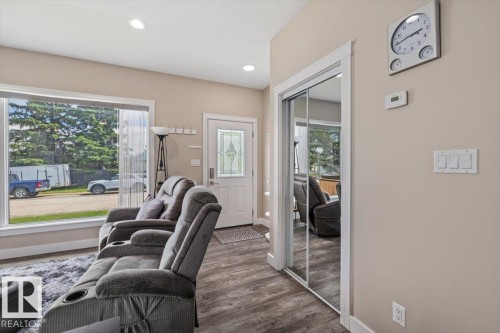Living room featuring wood-finish flooring, recessed lighting, and a large front-facing window - 4708 47A Avenue, Onoway, AB 