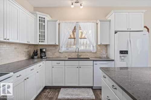 Kitchen featuring white shaker-style cabinetry, dark countertops, and a subway tile backsplash - 4708 47A Avenue, Onoway, AB 