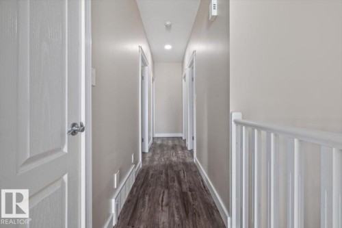 Hallway featuring wood-finish flooring, recessed lighting, neutral wall paint, white trim, and a white stair railing - 4708 47A Avenue, Onoway, AB 