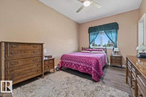 Spacious room featuring wood-finish flooring, a contemporary ceiling fan, and a large window with exterior views - 4708 47A Avenue, Onoway, AB 