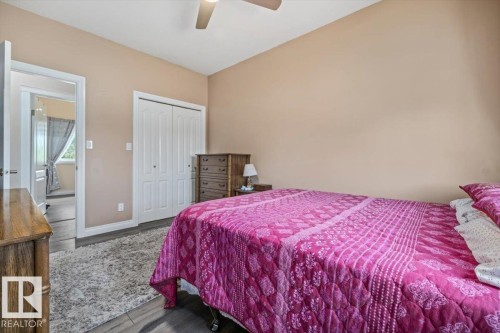 Bedroom featuring wood-finish flooring, a ceiling fan, and bi-fold closet doors - 4708 47A Avenue, Onoway, AB 
