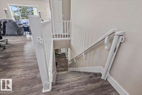 Interior staircase featuring carpeted treads, white railing, and a wall-mounted handrail - 4708 47A Avenue, Onoway, AB 