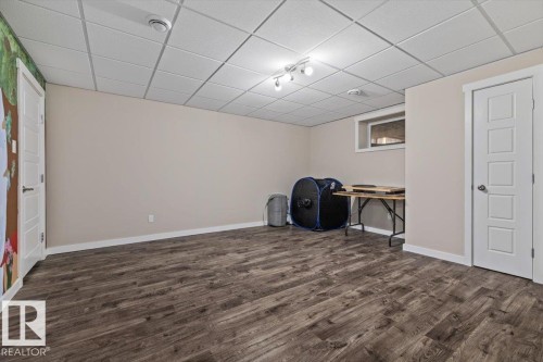 Spacious room featuring wood-finish flooring, light beige walls, and a white grid ceiling - 4708 47A Avenue, Onoway, AB 