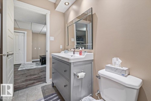 Bathroom featuring a contemporary gray vanity with integrated sink, a rectangular mirror, and recessed lighting - 4708 47A Avenue, Onoway, AB 