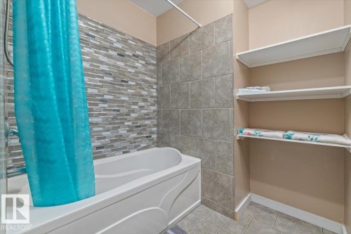 Bathtub with decorative mosaic tile surround and coordinating large format tile walls - 4708 47A Avenue, Onoway, AB 