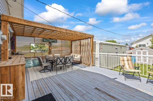 Expansive outdoor deck featuring a wood pergola with slatted sides and roof, an integrated hot tub, and wood-finish flooring - 4708 47A Avenue, Onoway, AB 