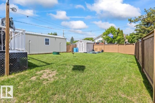 Expansive green lawn surrounded by a privacy fence, featuring a large shed with a window, and a smaller storage shed - 4708 47A Avenue, Onoway, AB 